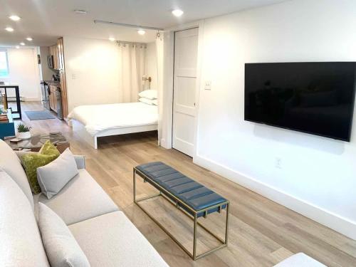 a living room with a couch and a tv on a wall at Fresh Modern Garden Level Kittery Studio in Kittery