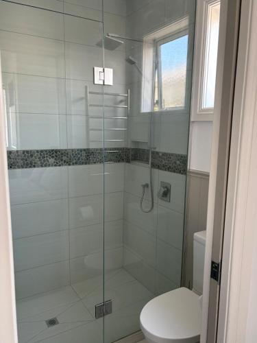 a bathroom with a glass shower with a toilet at Stylish Petone Stay in Lower Hutt