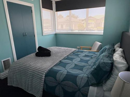 a bedroom with a bed with a black hat on it at Stylish Petone Stay in Lower Hutt