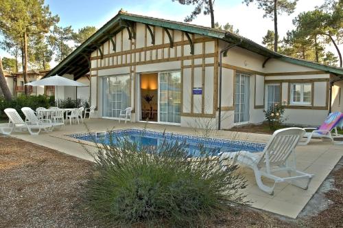 a house with a swimming pool in front of it at Résidence Odalys Les Greens du Bassin in Gujan-Mestras