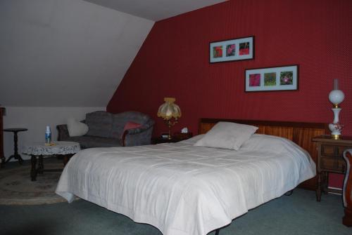 ein Schlafzimmer mit einem Bett und einer roten Wand in der Unterkunft La Rachère in Vayres-sur-Essonnes