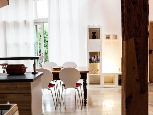 a kitchen with a wooden table and white chairs at Apartment Studio by Interhome in Schernfeld