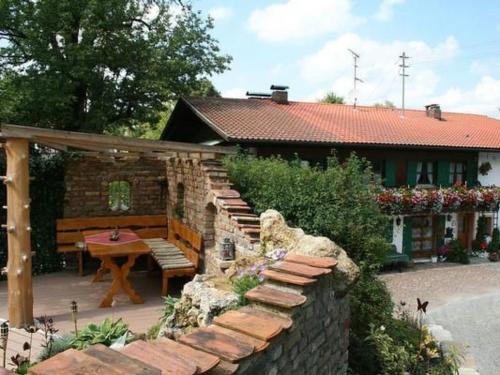 a house with a stone wall and a table and a bench at Apartment Igel by Interhome in Bad Bayersoien