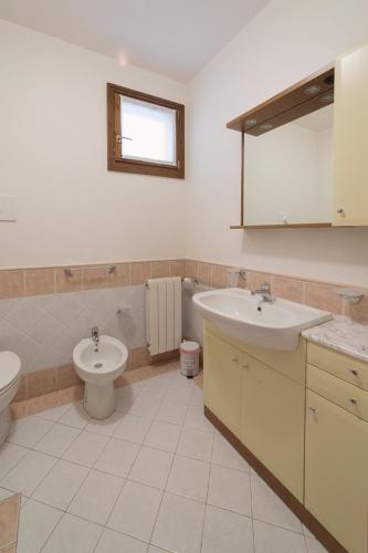a bathroom with two sinks and a toilet and a window at Blu Garda View in Polpenazze del Garda