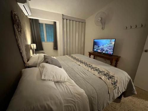 a bedroom with two beds and a flat screen tv at Casa Linda in Campeche