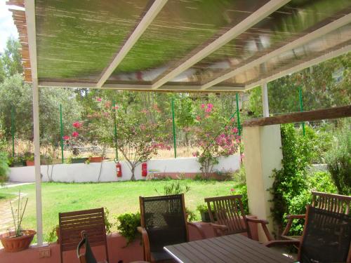 un patio con mesa y sillas y un jardín en B&B Su Tostainu, en Teulada