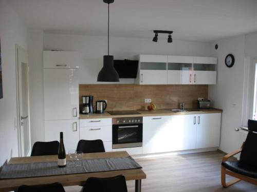 a kitchen with white cabinets and a table with a bottle of wine at Apartment Haus Budinger by Interhome in Alf