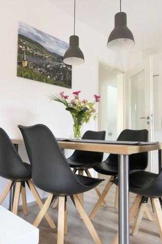 a dining room table with black chairs and a vase of flowers at Apartment Haus Budinger by Interhome in Alf