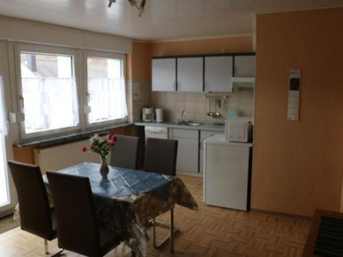 a kitchen with a table and chairs and a kitchen with a refrigerator at Apartment Haus Budinger by Interhome in Alf