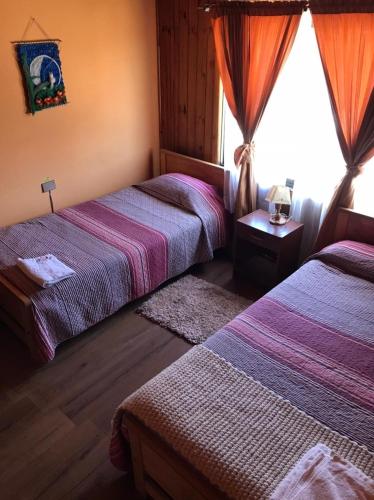 een hotelkamer met twee bedden en een raam bij Hostal Lucerna in Curanipe