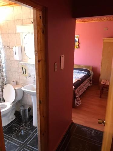 een badkamer met een toilet, een wastafel en een bed bij Hostal Lucerna in Curanipe