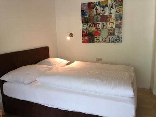 a bed with white sheets and a painting on the wall at Hotel & Appartements Alpenresidenz Viktoria in Neustift im Stubaital