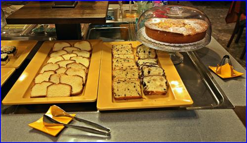 a table with two trays of bread and a cake at Hotel Meeting in Ciampino