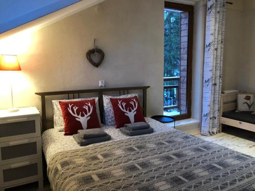 een slaapkamer met een bed met rode kussens en een raam bij Willa Avita in Karpacz