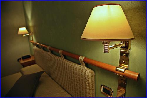 a lamp on a wall next to a bed in a room at Hotel Meeting in Ciampino