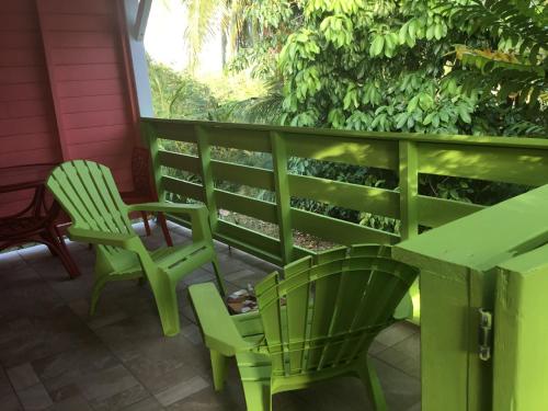 twee groene stoelen en een tafel op een veranda bij Résidence rose Cannelle in Grand-Bourg