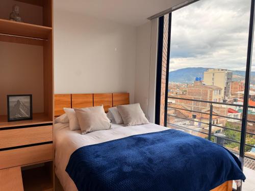 une chambre avec un lit et une grande fenêtre dans l'établissement Luminoso y Céntrico Loft con Balcón, à Sogamoso