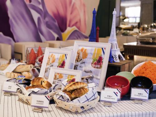 une table garnie de paniers de pâtisseries et la tour Eiffel dans l'établissement Mercure Hangzhou West Lake, à Hangzhou
