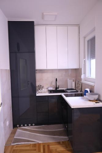 een keuken met zwart-witte kasten en een wastafel bij Splendid J&R apartman in Bijeljina