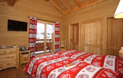 a bedroom with a red and white bed and a television at Odalys Chalet Prestige Lodge in Les Deux Alpes