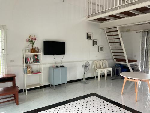 a living room with a tv and a staircase at Baan Klang Khao Mountain Viewบ้านกลางเขา เมาเทนวิว in Ban Pang Asok