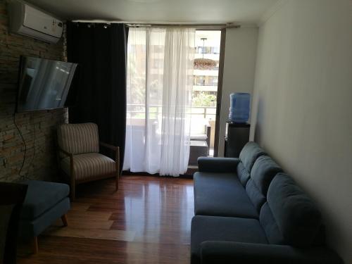 a living room with a blue couch and a window at departamento vacacional in Arica
