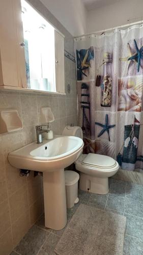 a bathroom with a sink and a toilet and a window at Dina's Beach House in Karpathos