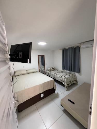 een slaapkamer met twee bedden en een flatscreen-tv bij Flats Brisa Antunes in Maragogi