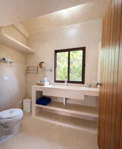 a bathroom with a sink and a toilet and a window at Island Escape for Groups Hosted by Atenea Holbox in Holbox Island