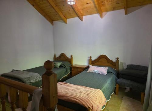 a bedroom with two twin beds and a chair at La esmeralda verde in Villa Ventana