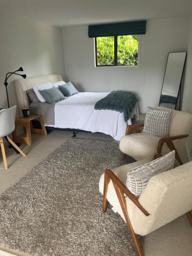 a bedroom with a bed and a couch and chairs at Myrtle St Guesthouse in Auckland