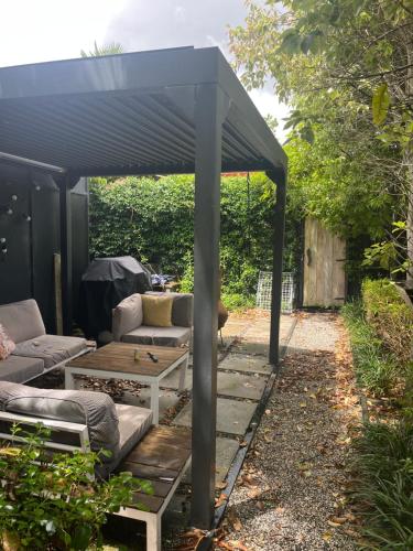 a pergola with a couch and a table in a yard at Myrtle St Guesthouse in Auckland