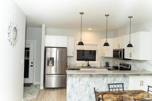 eine Küche mit weißen Schränken und einem Edelstahlkühlschrank in der Unterkunft Havilah's Place Regina in Regina