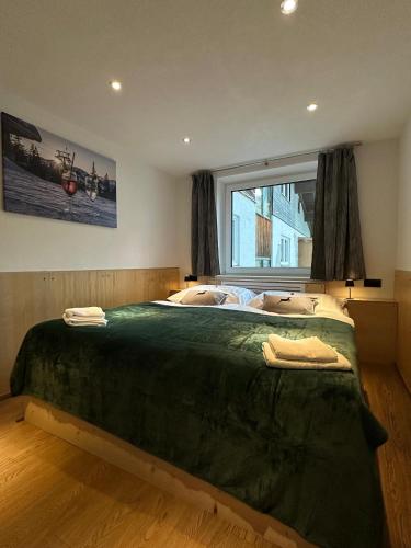a bedroom with a large green bed with a window at Haus Dienten Apartments nahe den Bergbahnen mit HochkönigCard in Dienten am Hochkönig