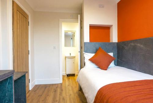 a bedroom with a bed with an orange wall at Thorpe Lodge Hotel in Peterborough