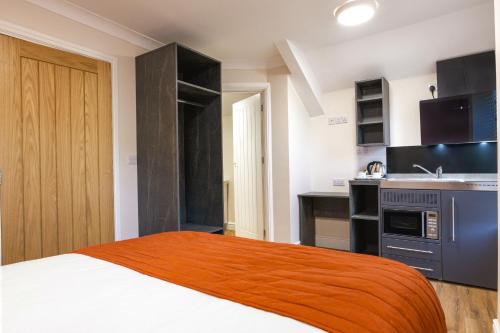 a small bedroom with a bed and a kitchen at Thorpe Lodge Hotel in Peterborough