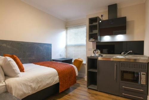 a bedroom with a bed and a kitchen with a sink at Thorpe Lodge Hotel in Peterborough
