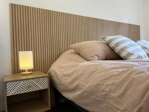 a bed with a wooden headboard and a lamp on a table at Next Door in Punta Arenas