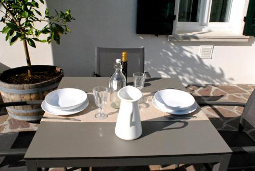 a gray table with white plates and glasses on it at Washington Apartments al Vittoriale in Gardone Riviera