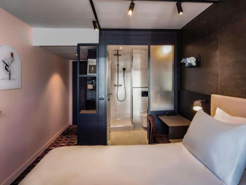 ein Hotelzimmer mit Bett und Dusche in der Unterkunft TRIBE Paris Batignolles in Paris