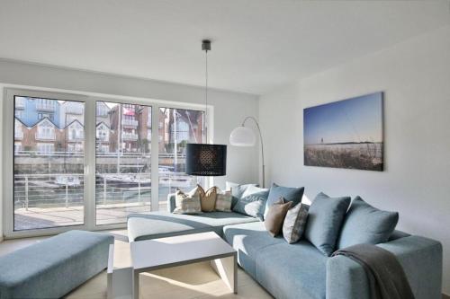 a living room with a blue couch and a large window at City Marina, CM24b in Cuxhaven