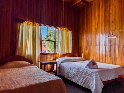 a bedroom with two beds with a teddy bear sitting on the bed at Hotel El Atardecer in Monteverde Costa Rica