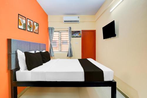 a bedroom with a bed with an orange wall at Collection O Electronic City in Bangalore