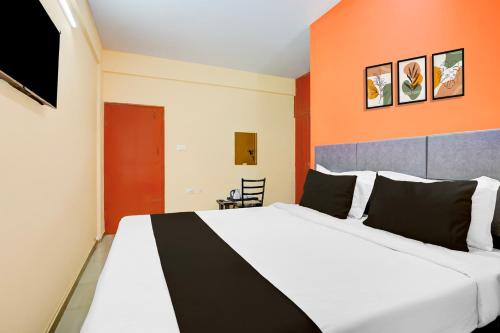a bedroom with a large white bed with an orange wall at Collection O Electronic City in Bangalore