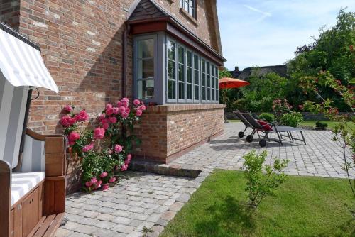 a brick house with a bench and pink flowers at Simons Hüs in Oldsum