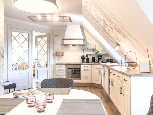 una cucina con armadi bianchi e un tavolo con bicchieri di De Utkieker a Witzwort
