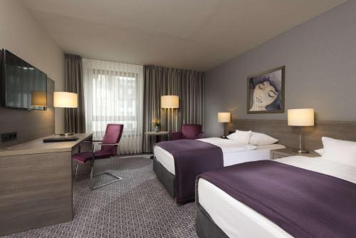 a hotel room with two beds and a desk at Maritim Hotel Königswinter in Königswinter