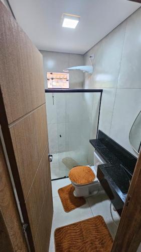 a bathroom with a toilet and a glass shower at Casa da Praia Bem Viver in Santa Cruz Cabrália