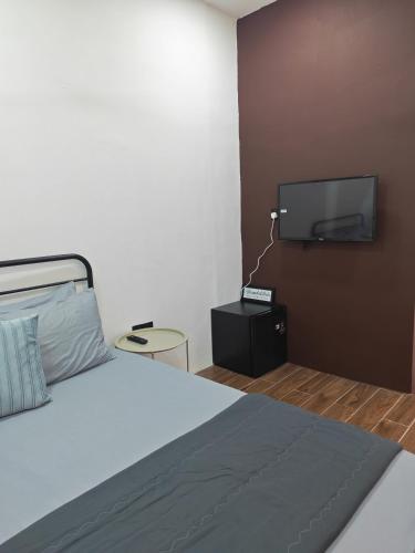 a bedroom with a bed and a flat screen tv at Rumah Comel Temerloh Studio in Temerloh