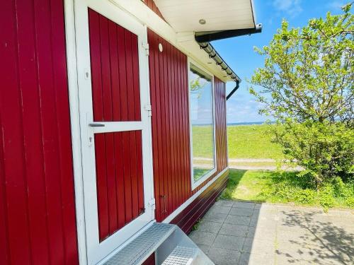 a red barn with a red door and a window at Strandhaus James Cook Teichhof Fehmarn in Wenkendorf